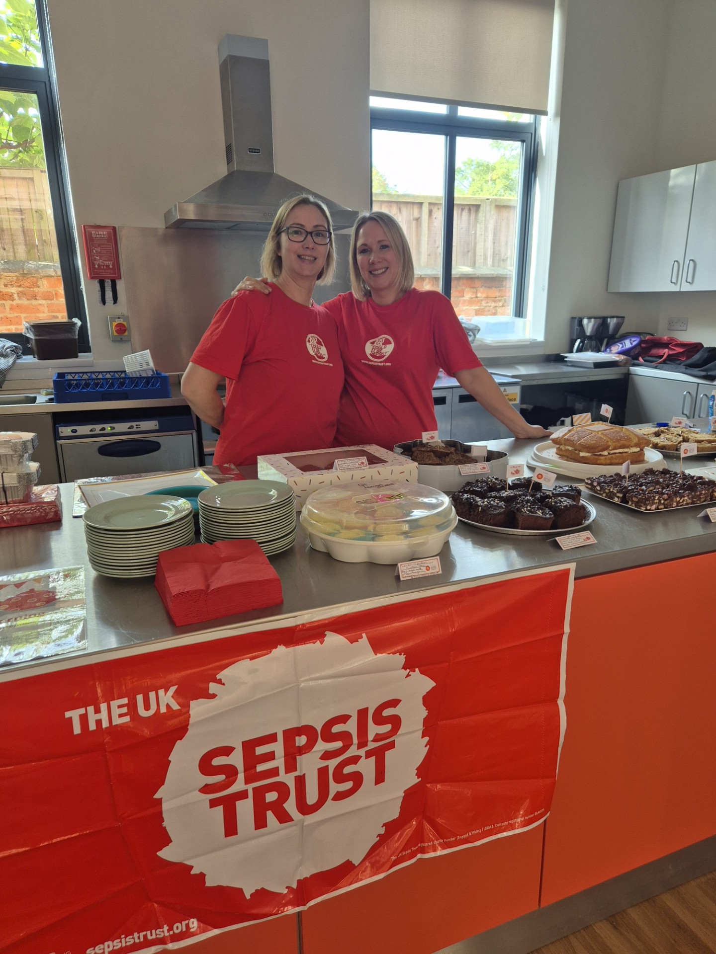 Two women running a UKST charity coffee morning with a bake stand