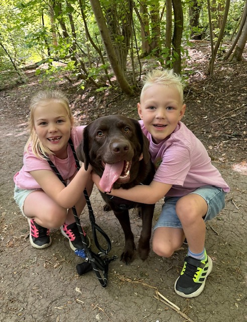 Brother and sister smiling while holding a dog.